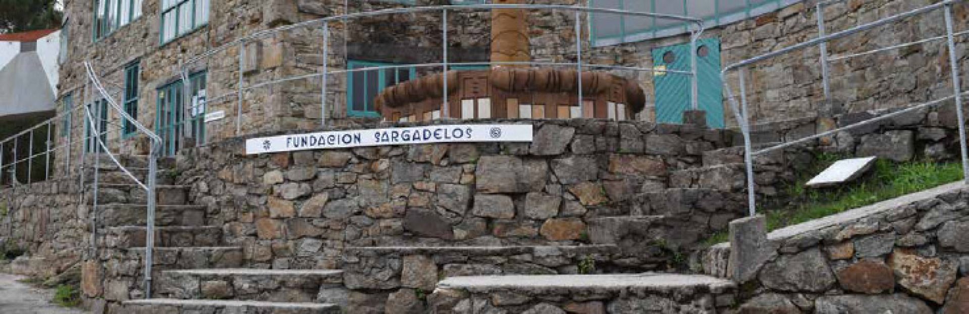 Stone wall with a sign reading 'Fundacion Sargadelos' in an outdoor setting.